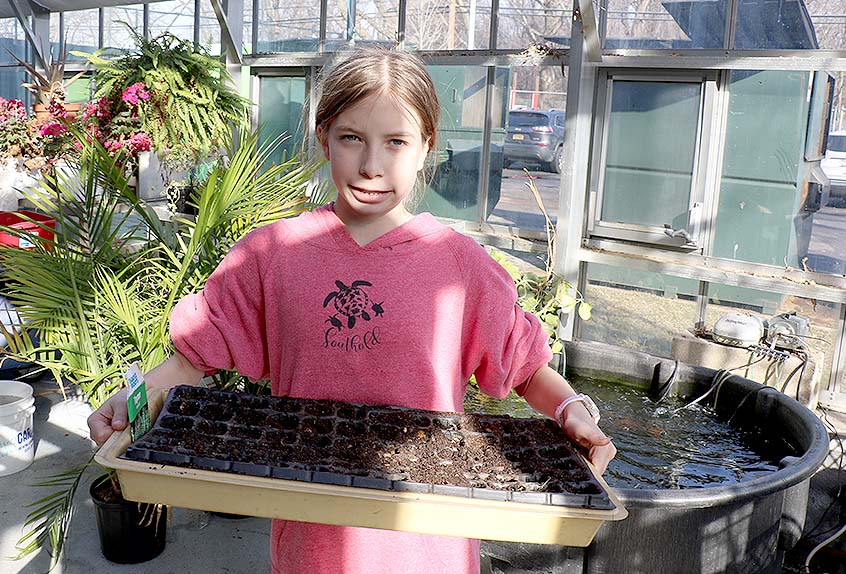 Urban Farming student with seed tray in front of koi pond